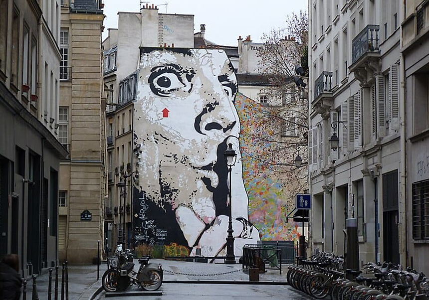 Mural representando a un hombre pidiendo silencio en una calle de París